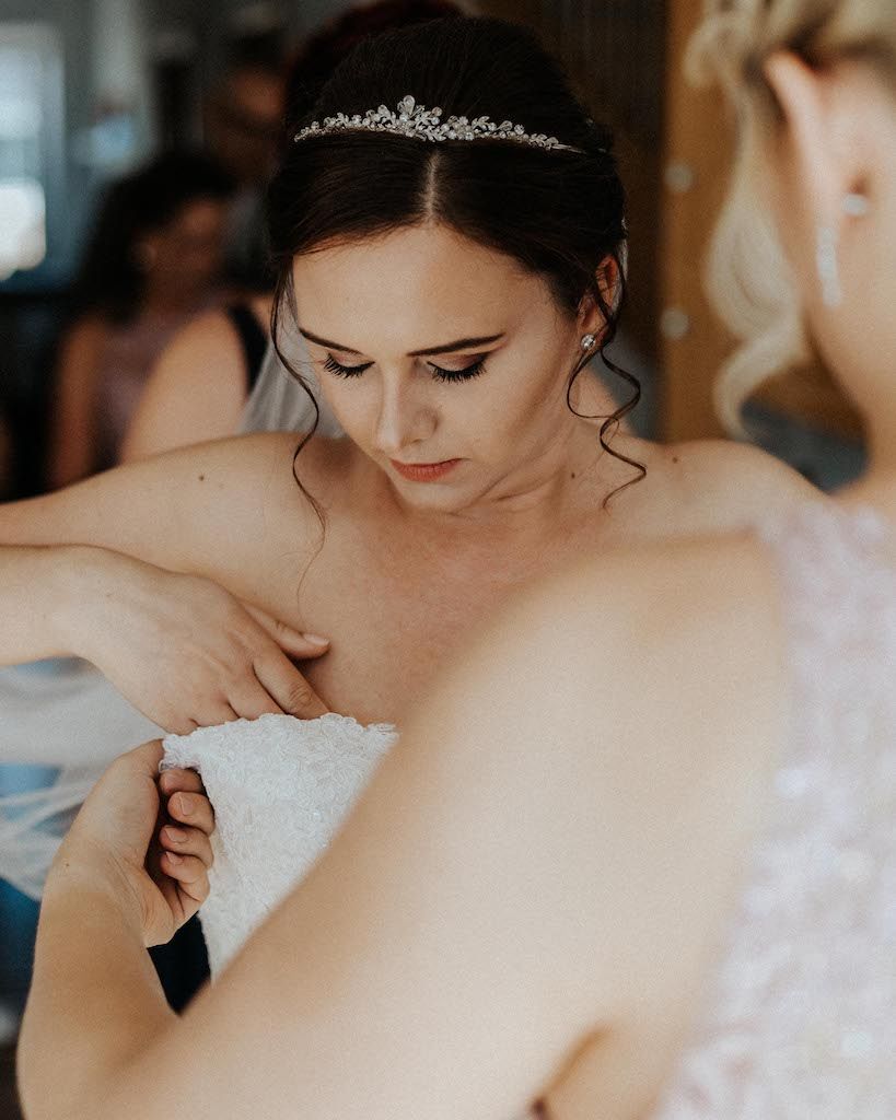 Braut zieht Hochzeitskleid an