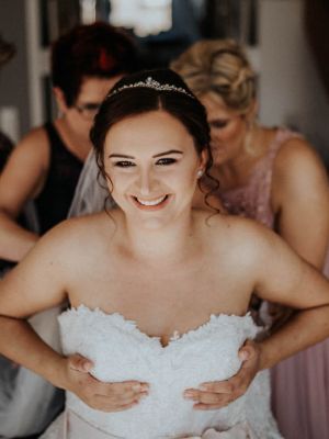 Braut bekommt Hilfe beim Anziehen des Brautkleids