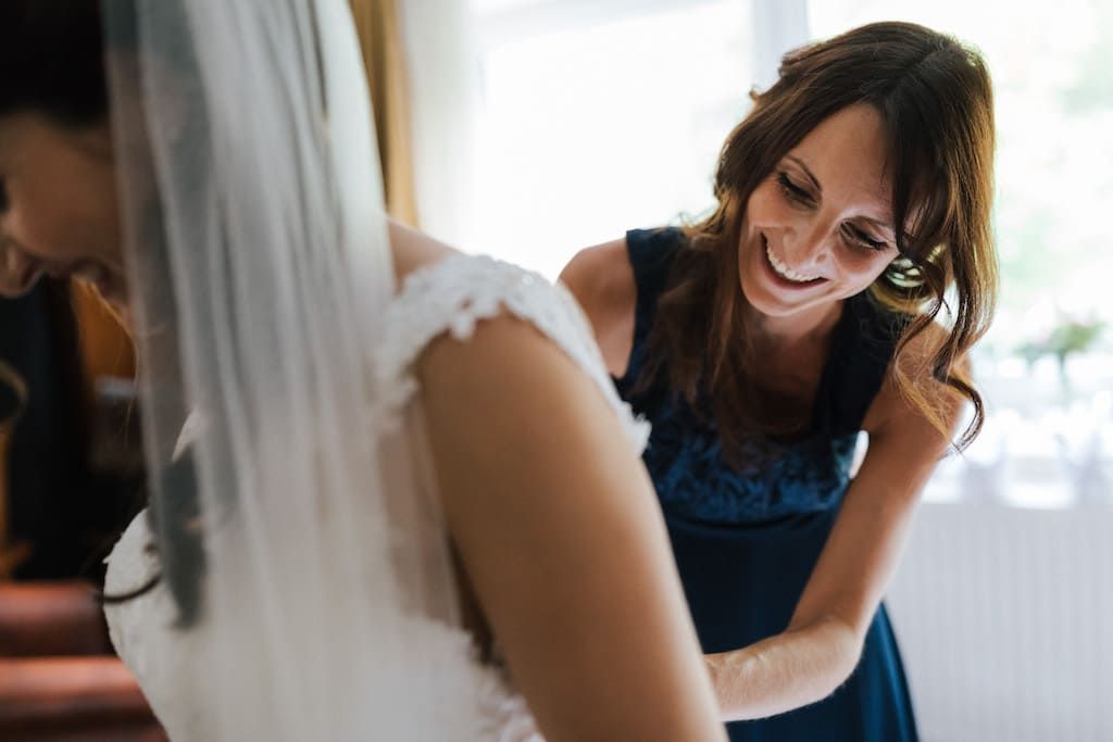 Brautjungfer hilft beim Kleid anziehen