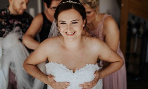 Braut zieht Hochzeitskleid an