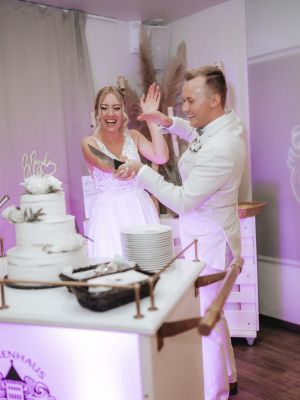 Braut und Bräutigam schneiden Hochzeitstorte an