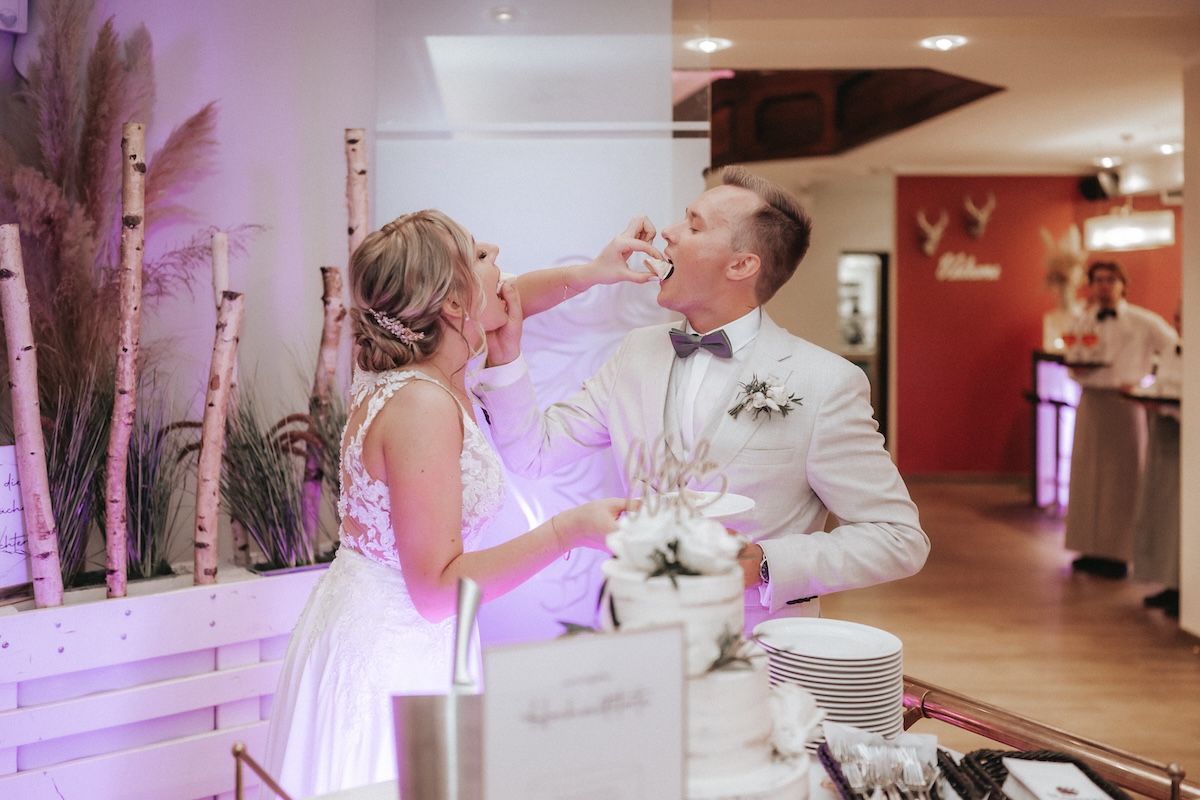 Braut und Bräutigam füttern sich gegenseitig mit Hochzeitstorte
