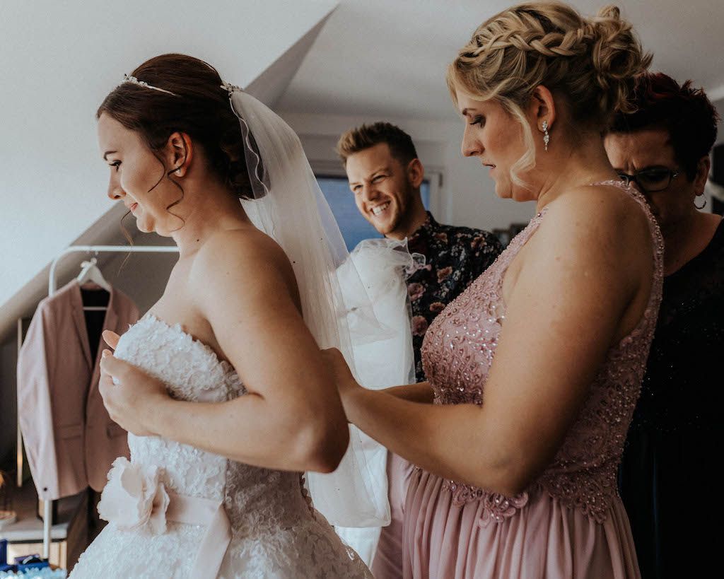 Braut hat Hilfe beim Hochzeitskleid anziehen