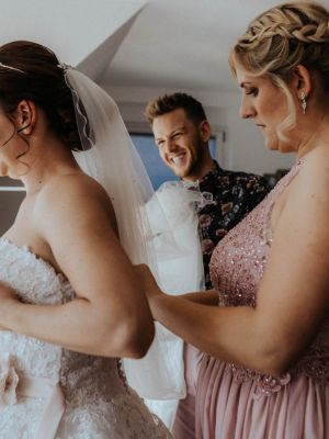 Braut und Freundin beim Anziehen des Brautkleids