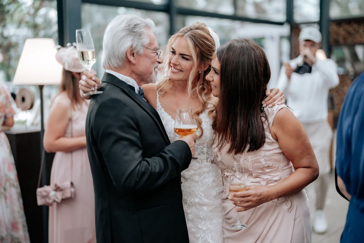 Braut spricht mit Vater und hat Getränk in der Hand