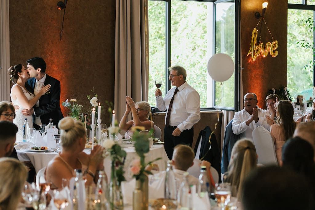 Hochzeitsgäste applaudieren und Brautpaar küsst sich