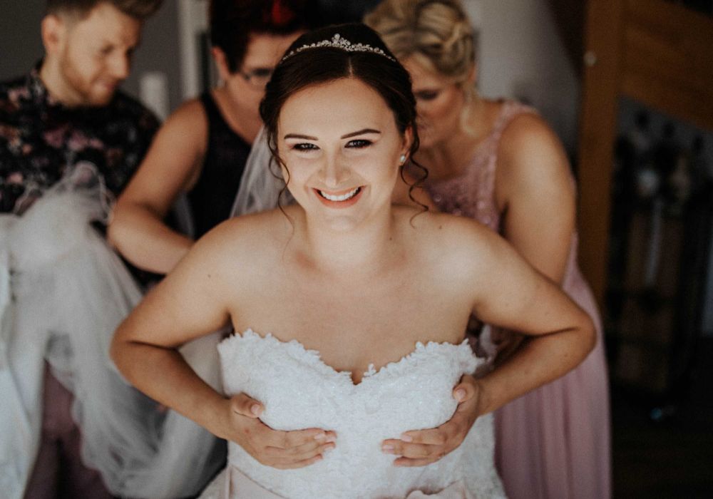 Braut zieht Hochzeitskleid an