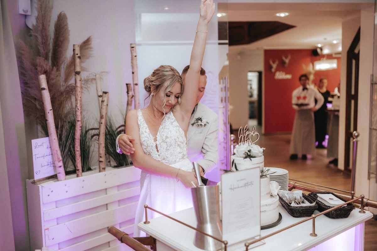 Braut und Bräutigam schneiden die Hochzeitstorte an